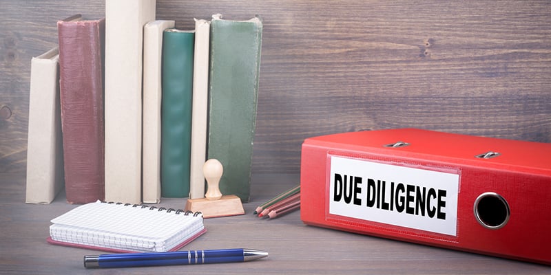 Red "Due Diligence" Binder on Office Desk with Pen and Paper