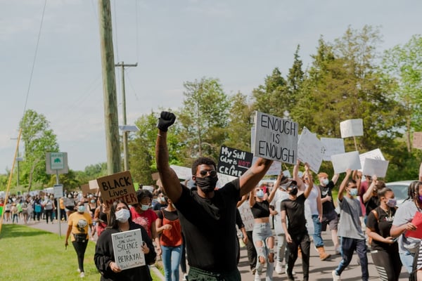 Protesters march with signs reading "enough is enough" and "black lives matter"
