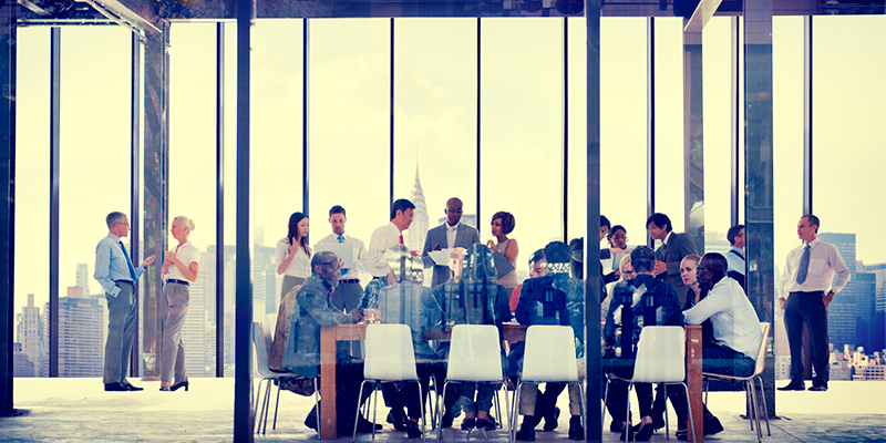 Looking in large windows of meeting room with board meeting taking place