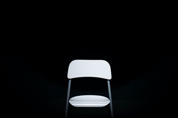 Blog header image: an empty white chair against a black background