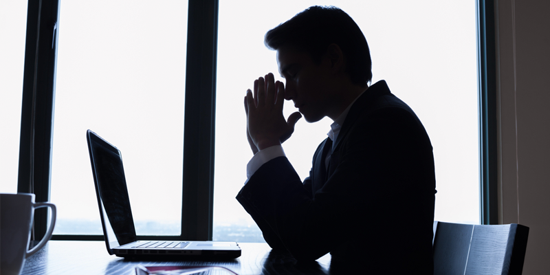 Frustrated silhouette of man at desk in meeting room office